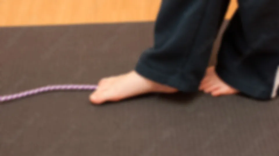 A child’s bare feet walking along a balance rope
