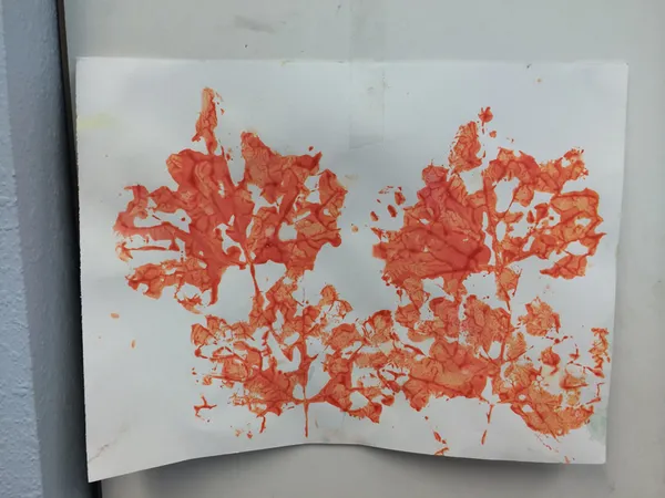 Orange handprint paintings drying on paper