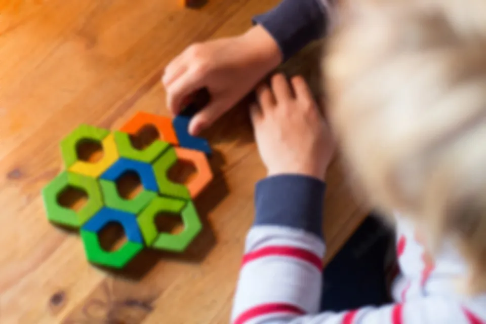 A child fitting hexagon pieces into a wooden puzzle