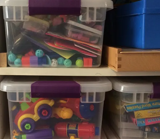 Clear bins of toys and manipulatives stacked on a shelf