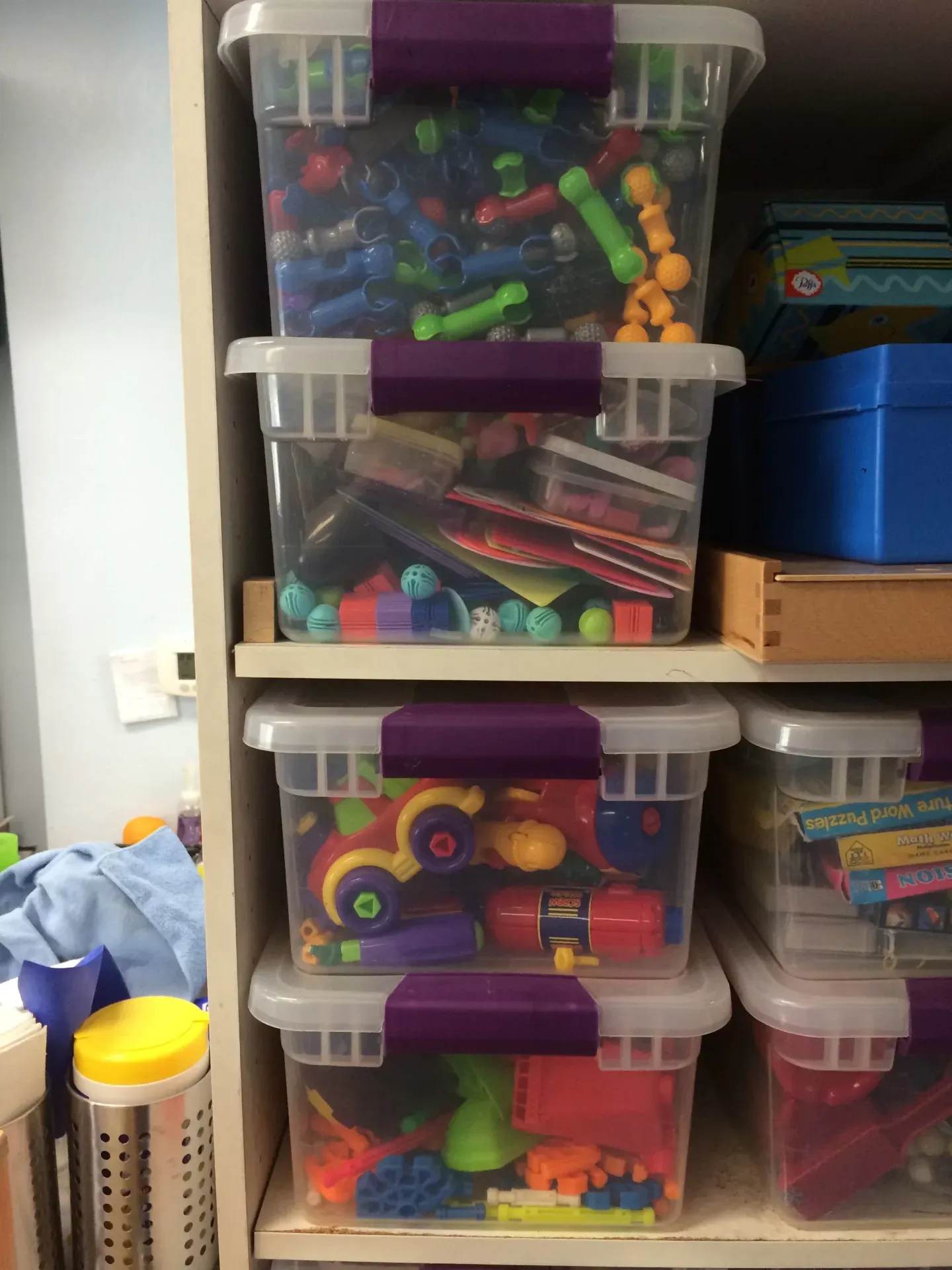 Bins of sensory toys and fidgets on the therapy room shelves