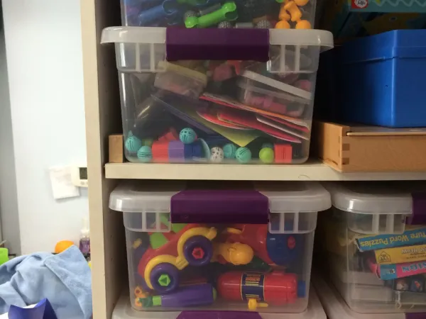 Bins of sensory toys and fidgets on the therapy room shelves